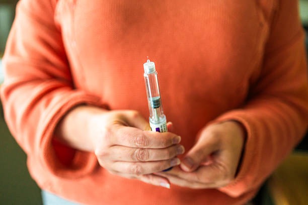 Person holding an injection pen at home showing a beginner's guide to starting Tirzepatide injection treatment.