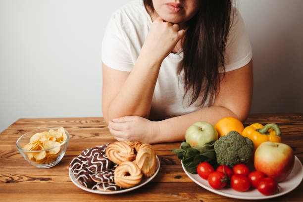 Woman sitting at a table with reduced interest in food showing how Tirzepatide effectively reduces food cravings.