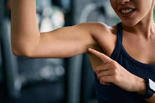 Woman noticing muscle loss in arms caused by cortisol slowing weight loss.
