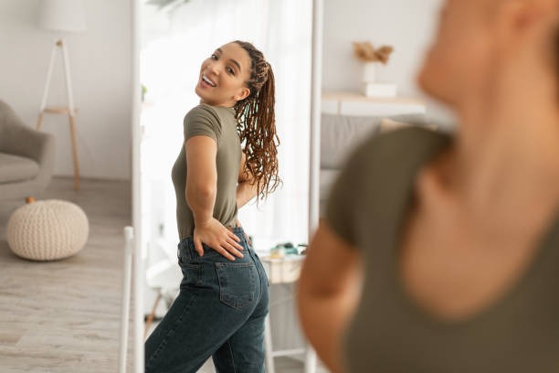 Body confidence gained as woman admires mirror reflection from peptide for weight loss.
