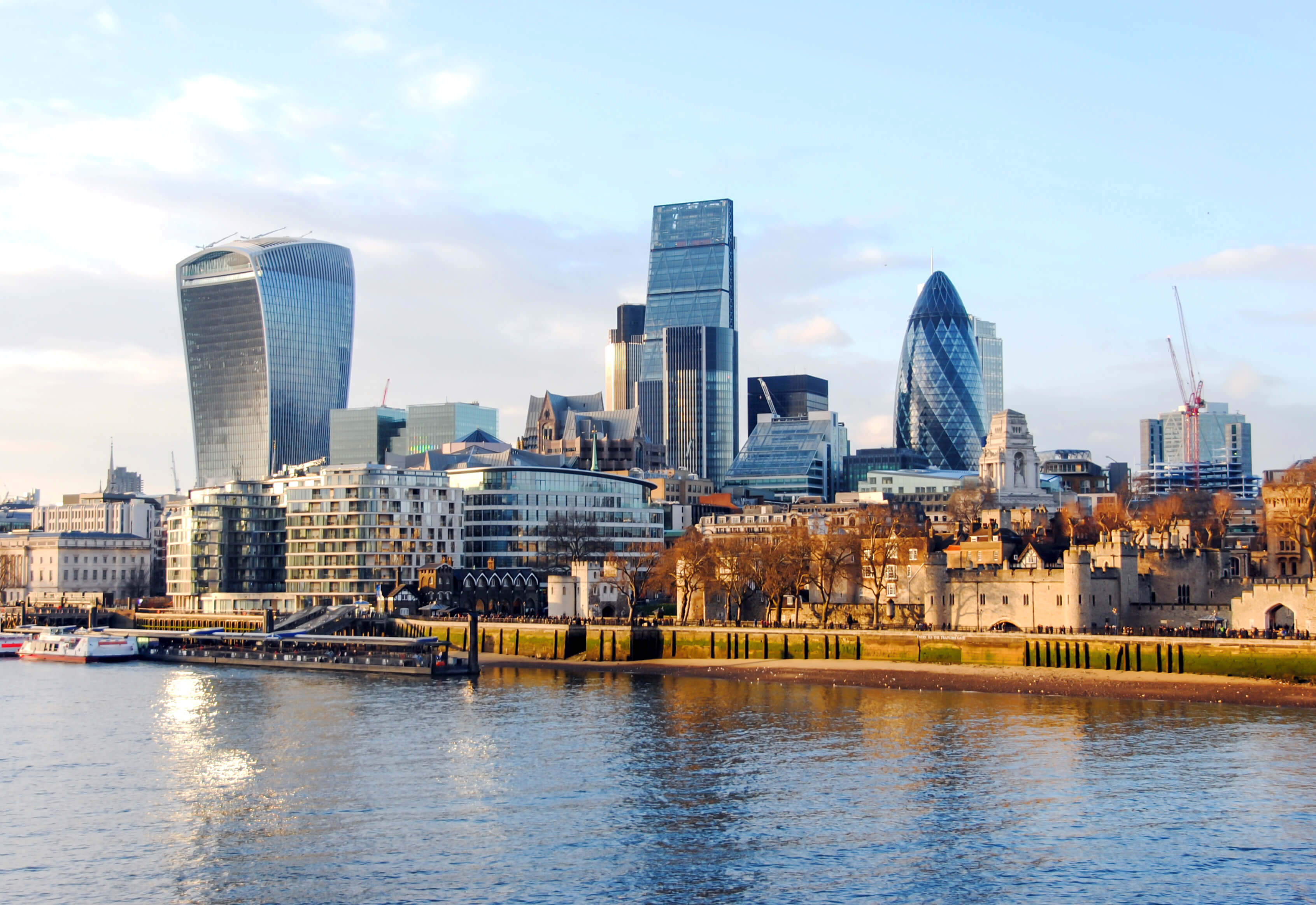 London skyline with River Thames, modern skyscrapers, and historic buildings at sunset.