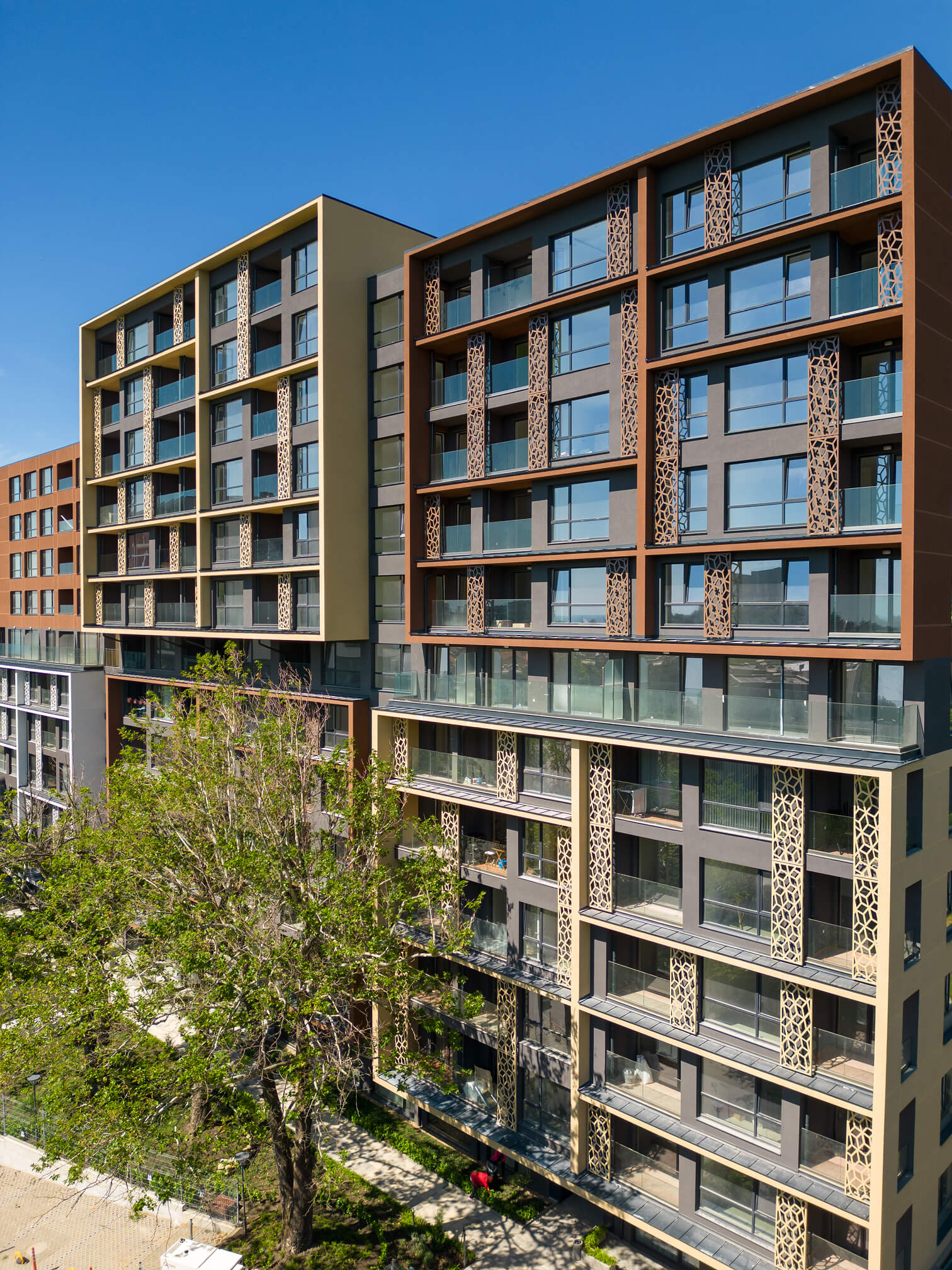 Modern multi-story apartment buildings with decorative panels and large windows under a clear blue sky.