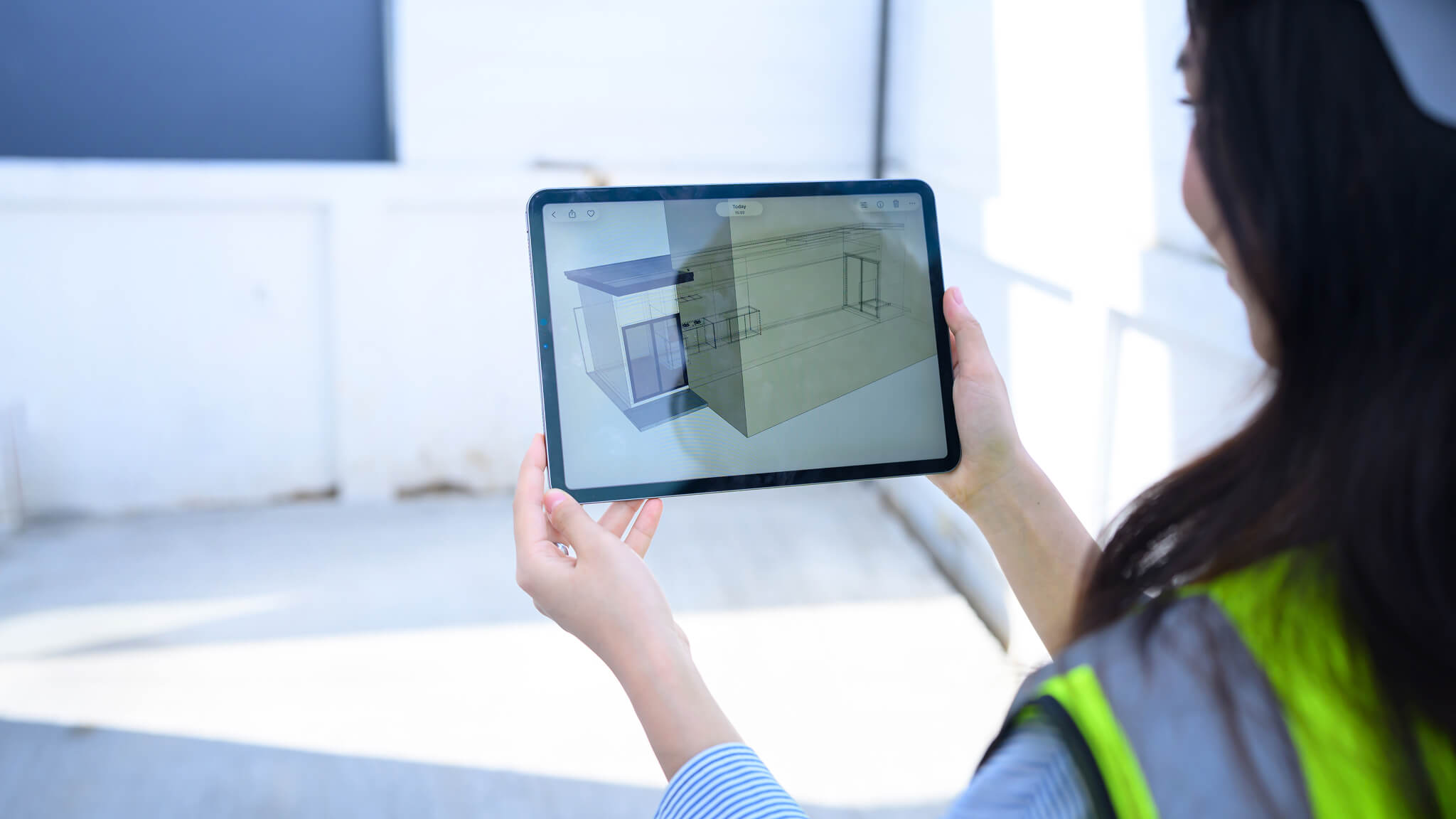 Person holding tablet showing a 3D architectural design of a building.