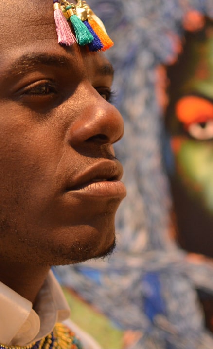 Close-up of an African-American man standing proudly while wearing a tribal head dress and jewelry.