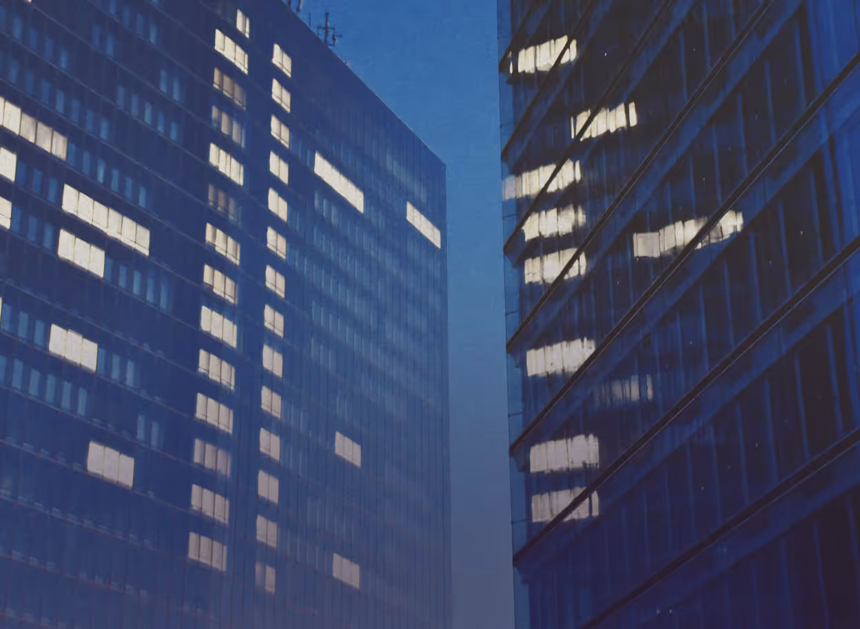 Two large buildings with light in some windows