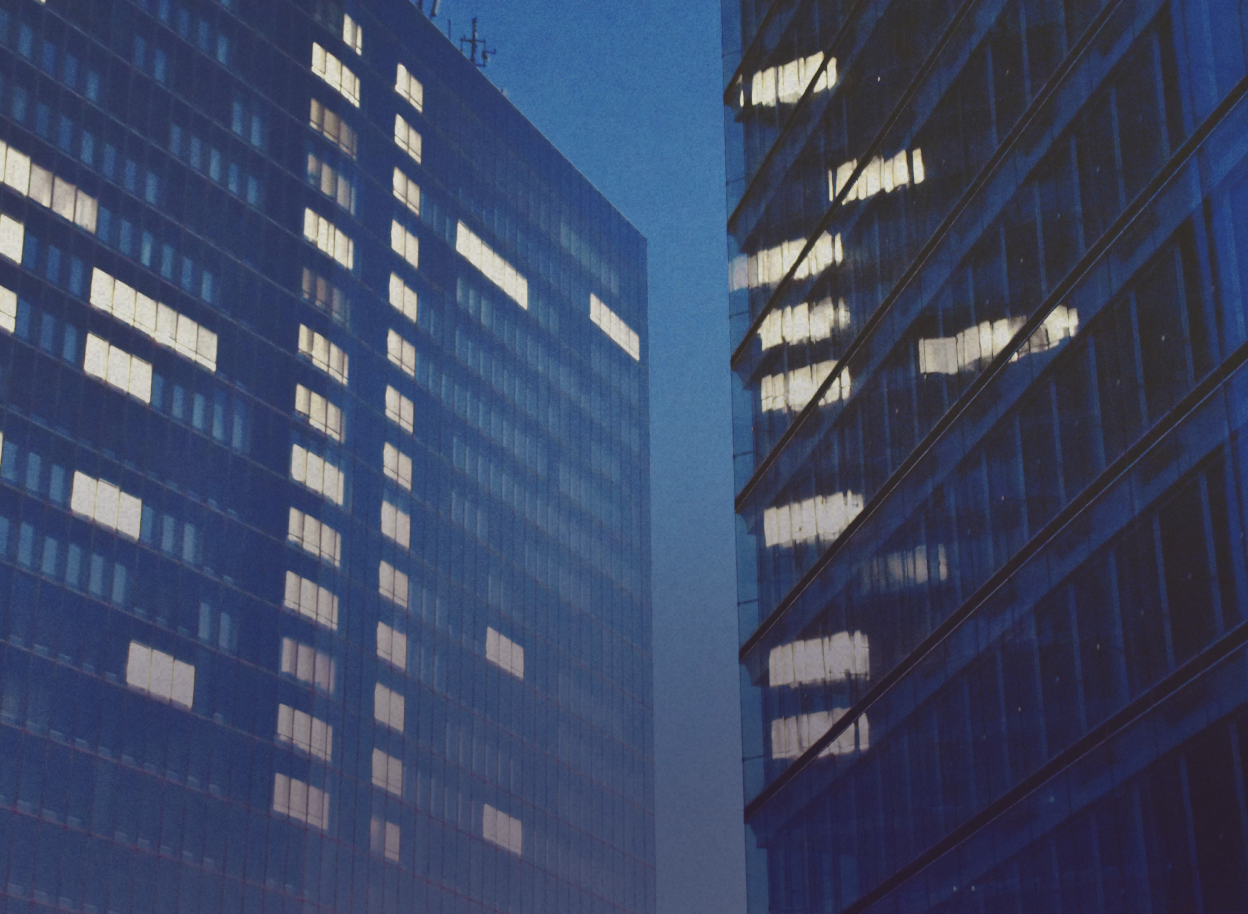 Two large buildings with light in some windows