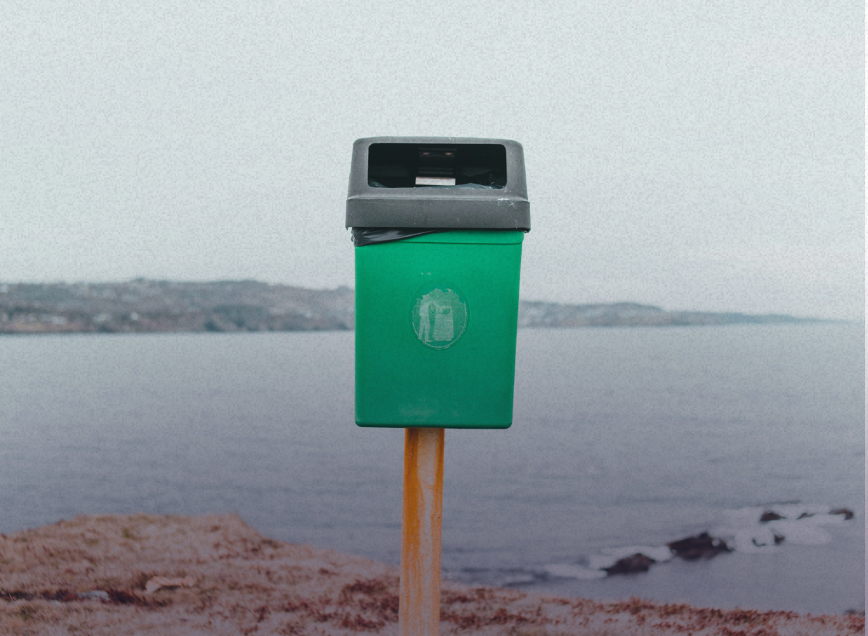 A trash container in front of a sea view