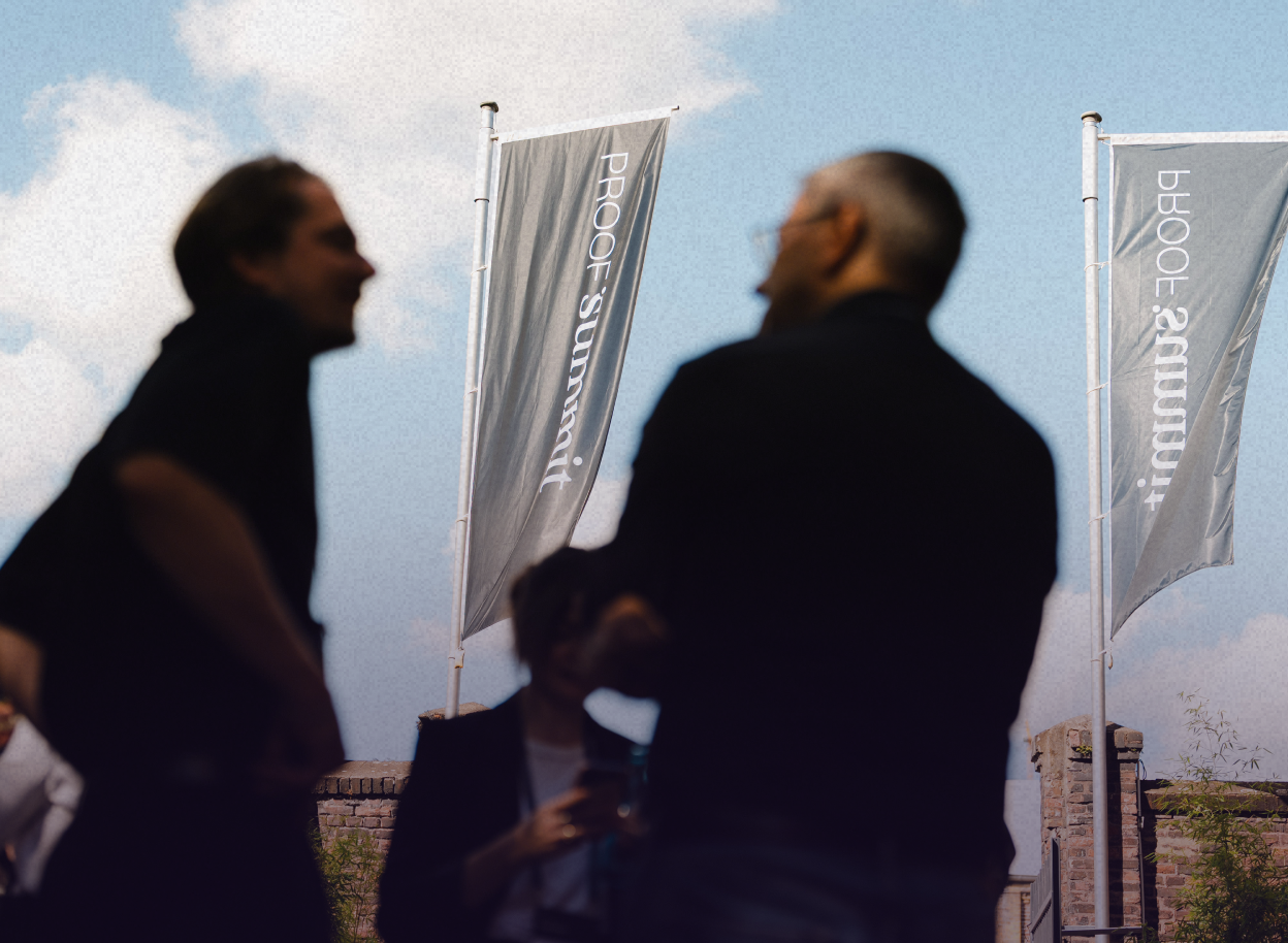 Zwei Personen unterhalten sich vor Flaggen vom PROOF Summit