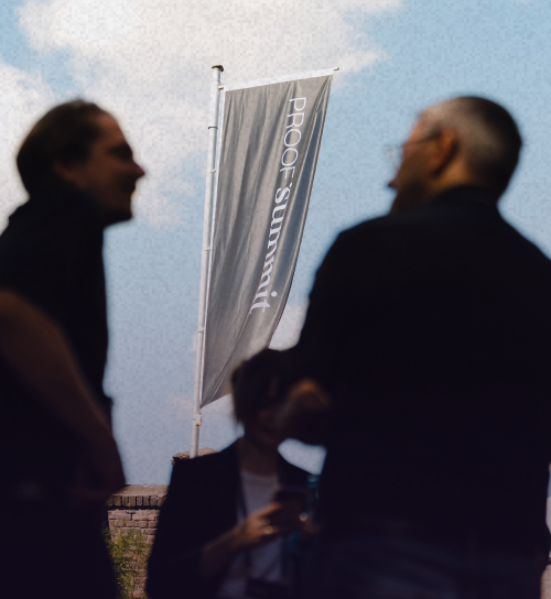 Zwei Personen unterhalten sich vor Flaggen vom PROOF Summit