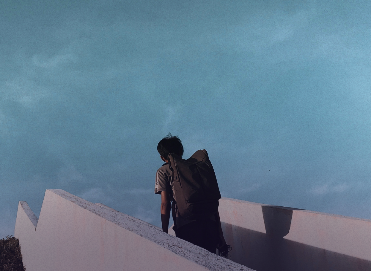 A man with a backpack walking up some stairs