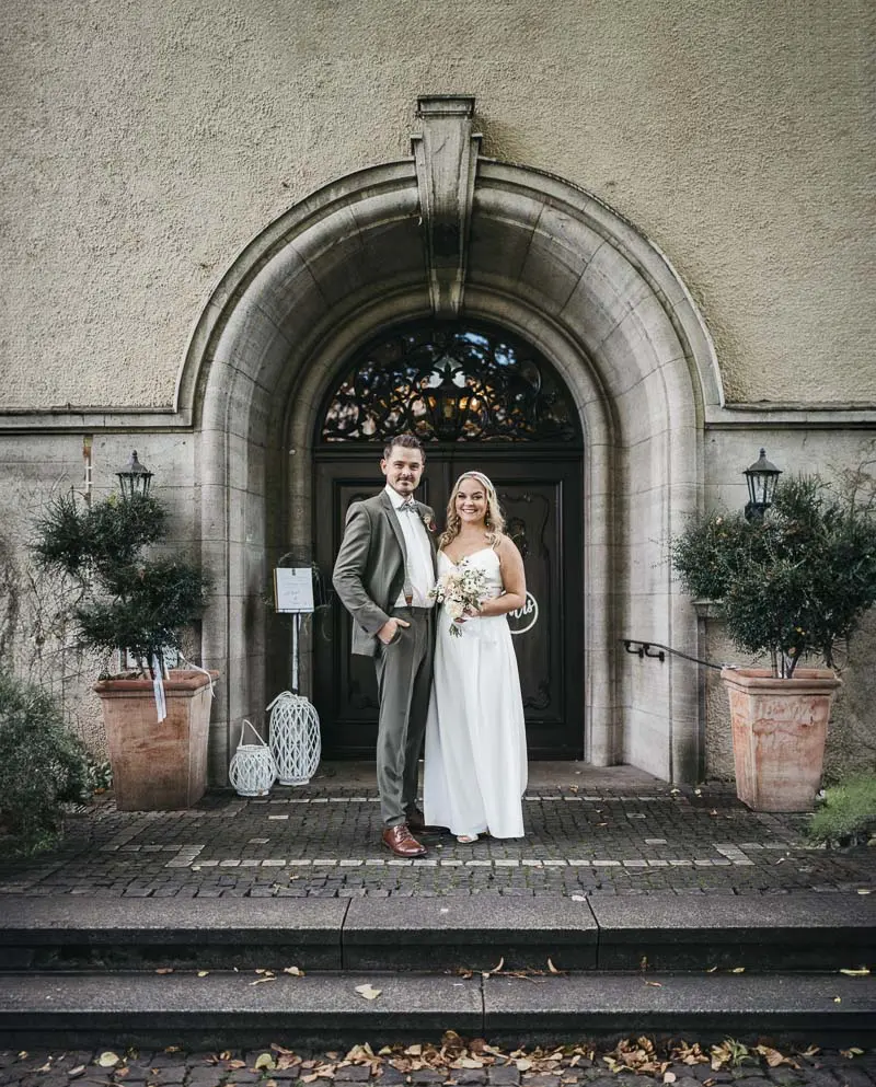 Brautpaar steht vor Eingang am Schloss Styrum