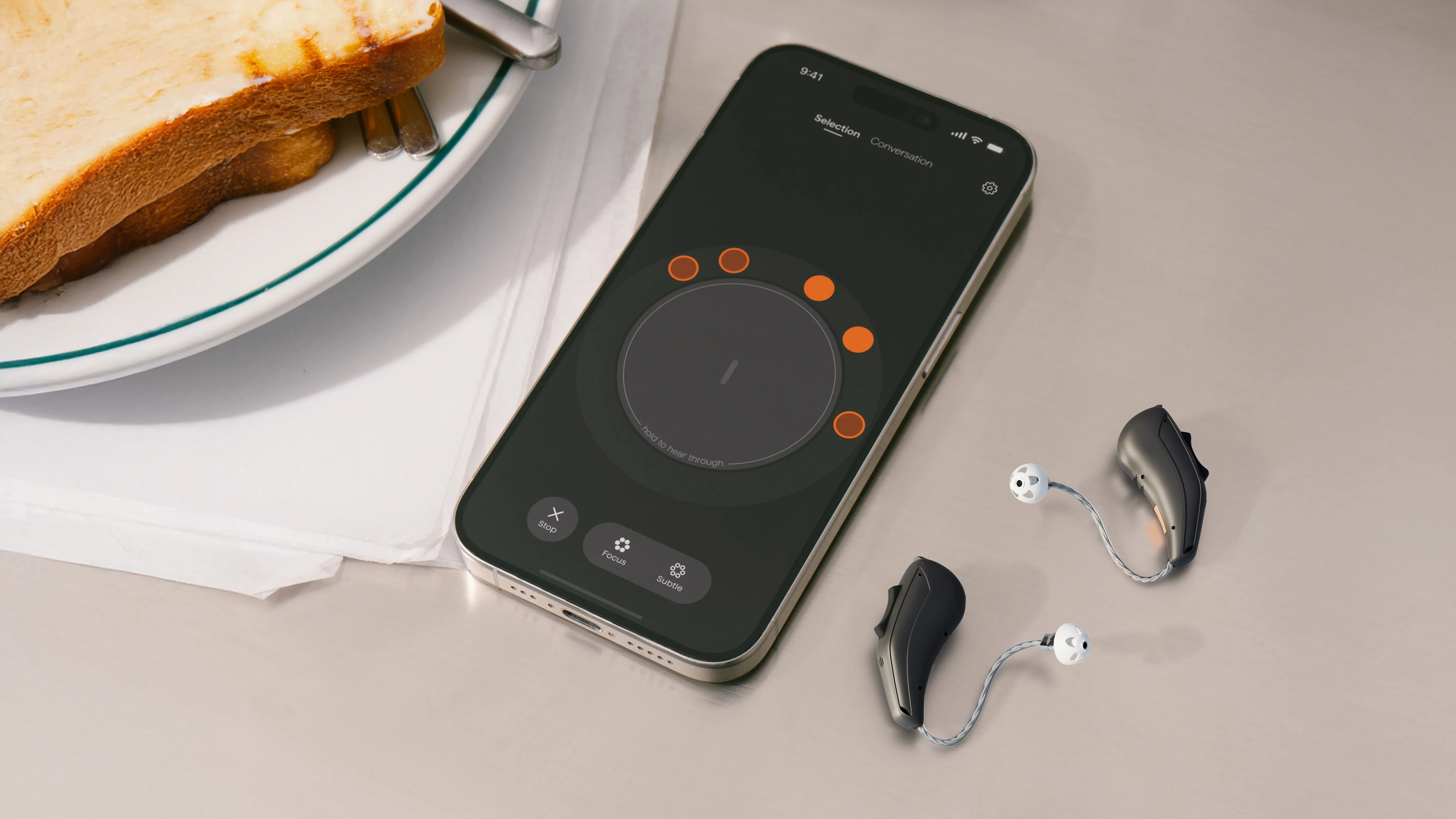 Smartphone with Voice Select App laying on a table next to hearing aids and a sandwich