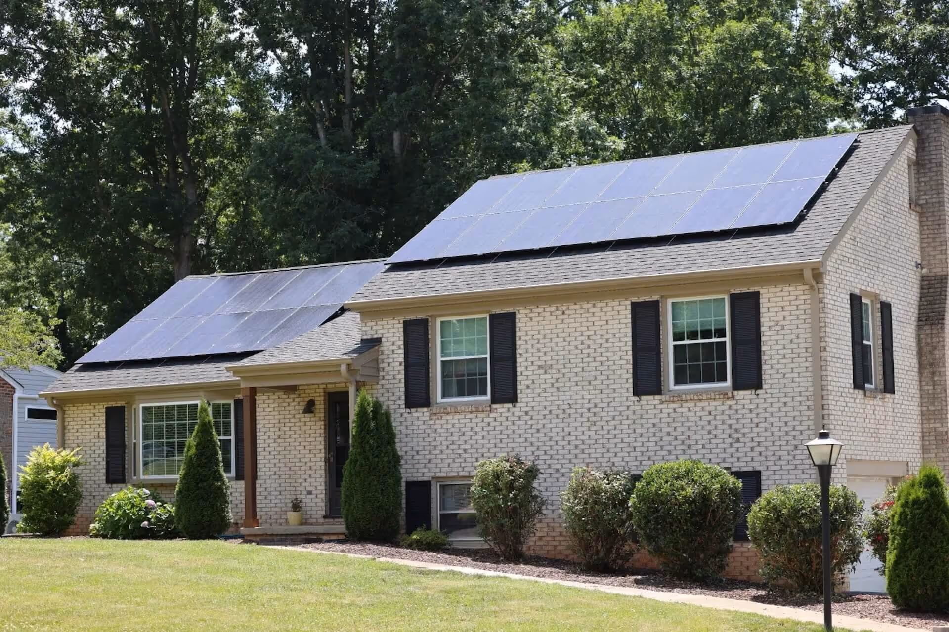 House with solar panels on the roof and well-maintained landscaping.