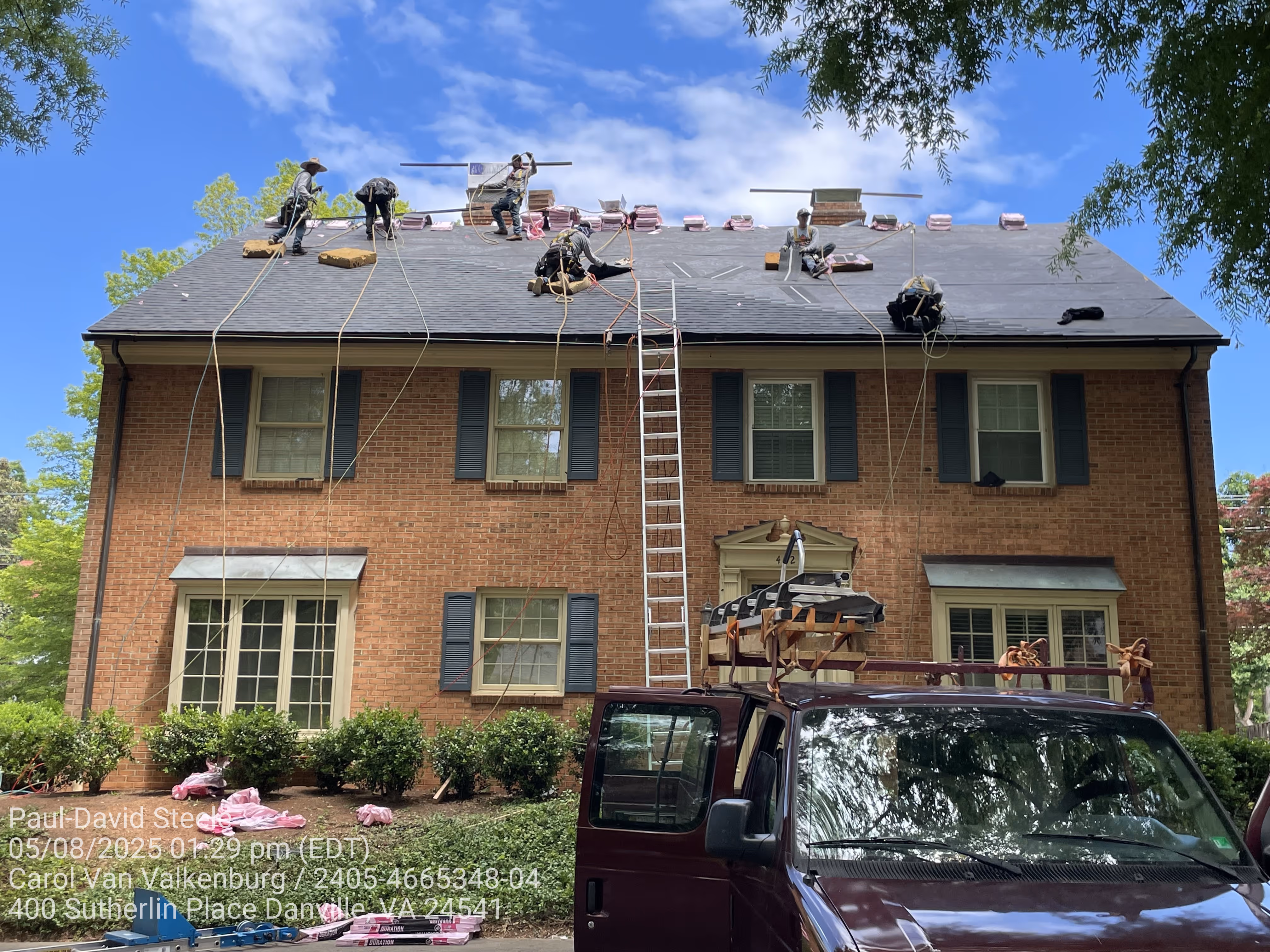 Several workers installing a new shingle roof.