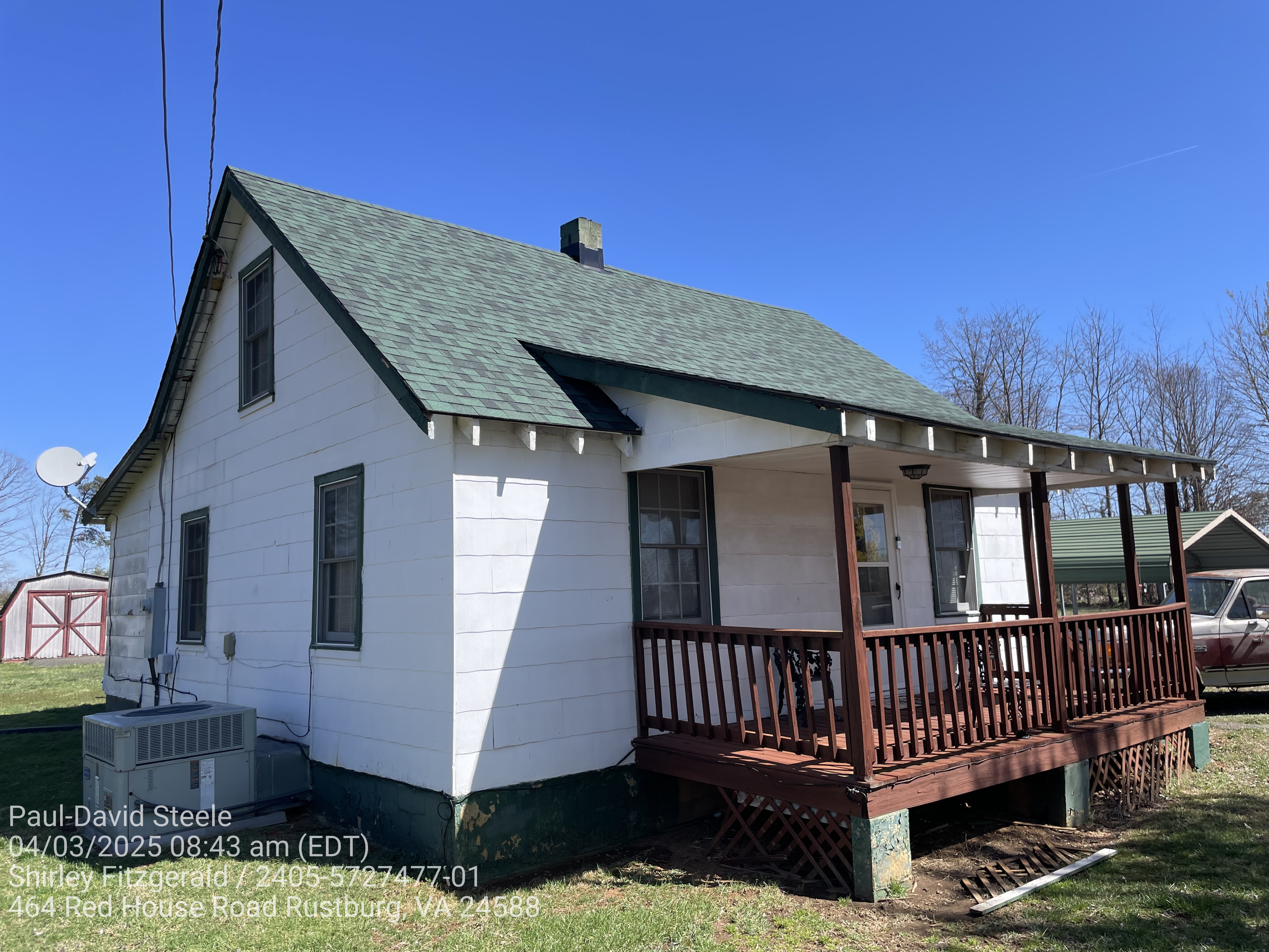 A small white house with Chateau Green shingles on the roof.