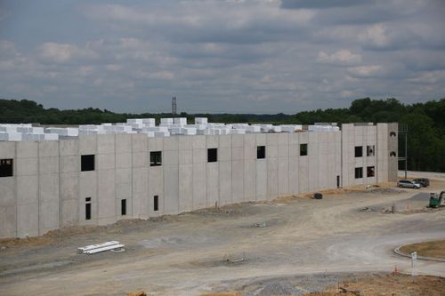 A building under construction with many windows, set against a cloudy sky.