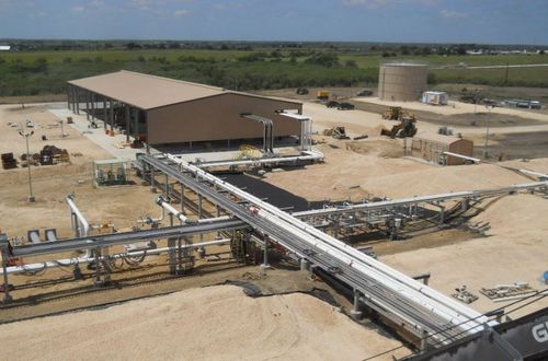 A large building stands prominently in the foreground with another large building visible in the background under a clear sky