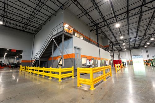 A set of yellow railings inside a warehouse, with a steel ceiling above and a concrete floor.