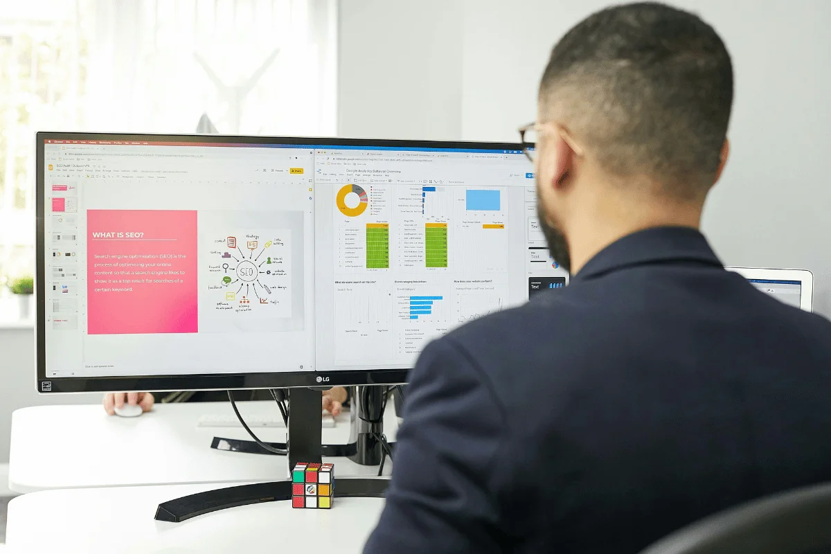 Marketer reviewing SEO presentation and analytics dashboards on dual monitors.