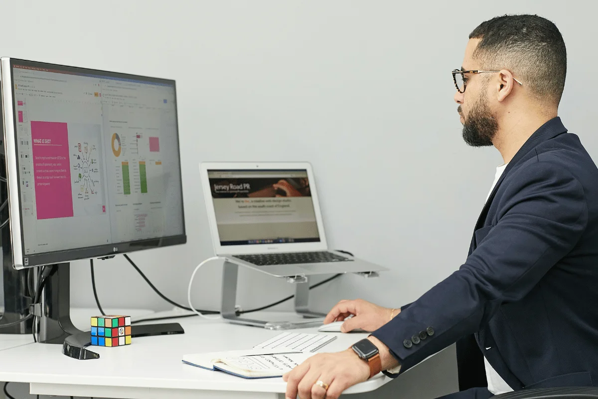 Business professional analyzing data on a large monitor at an office desk.