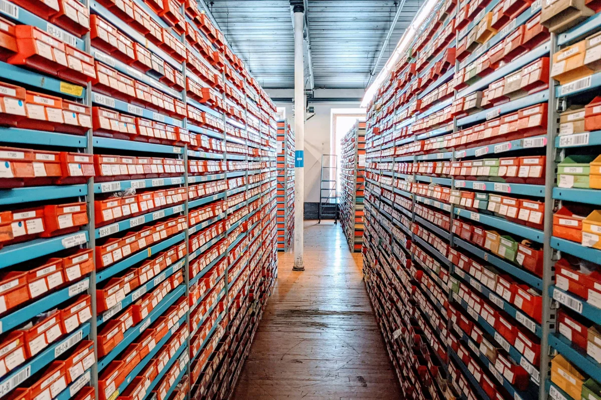 A narrow aisle between tall shelves filled with colorful storage boxes, organized systematically for easy access and retrieval.