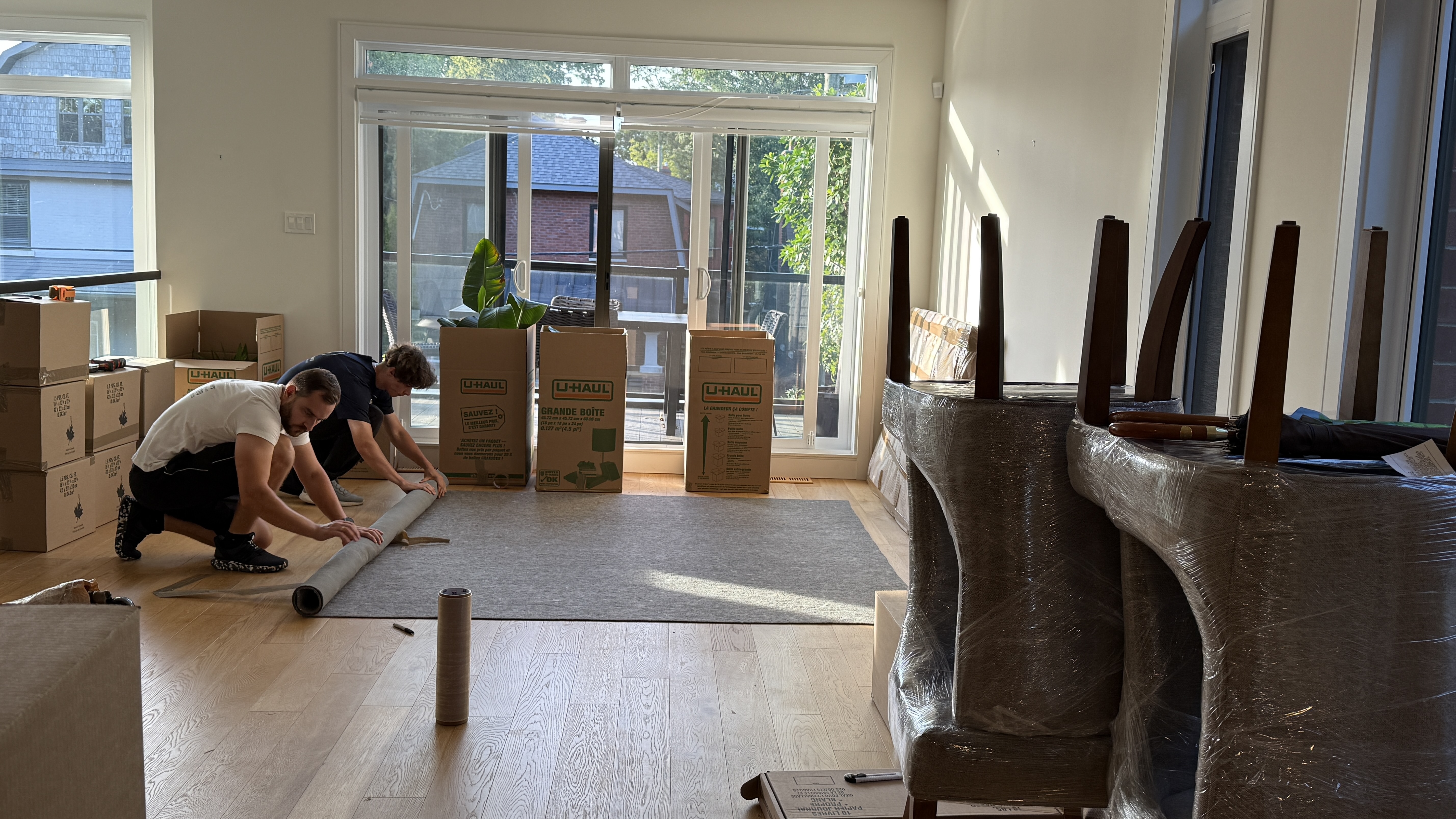 Ottawa pro movers rolling carpets in a dining room, well packed furniture around them