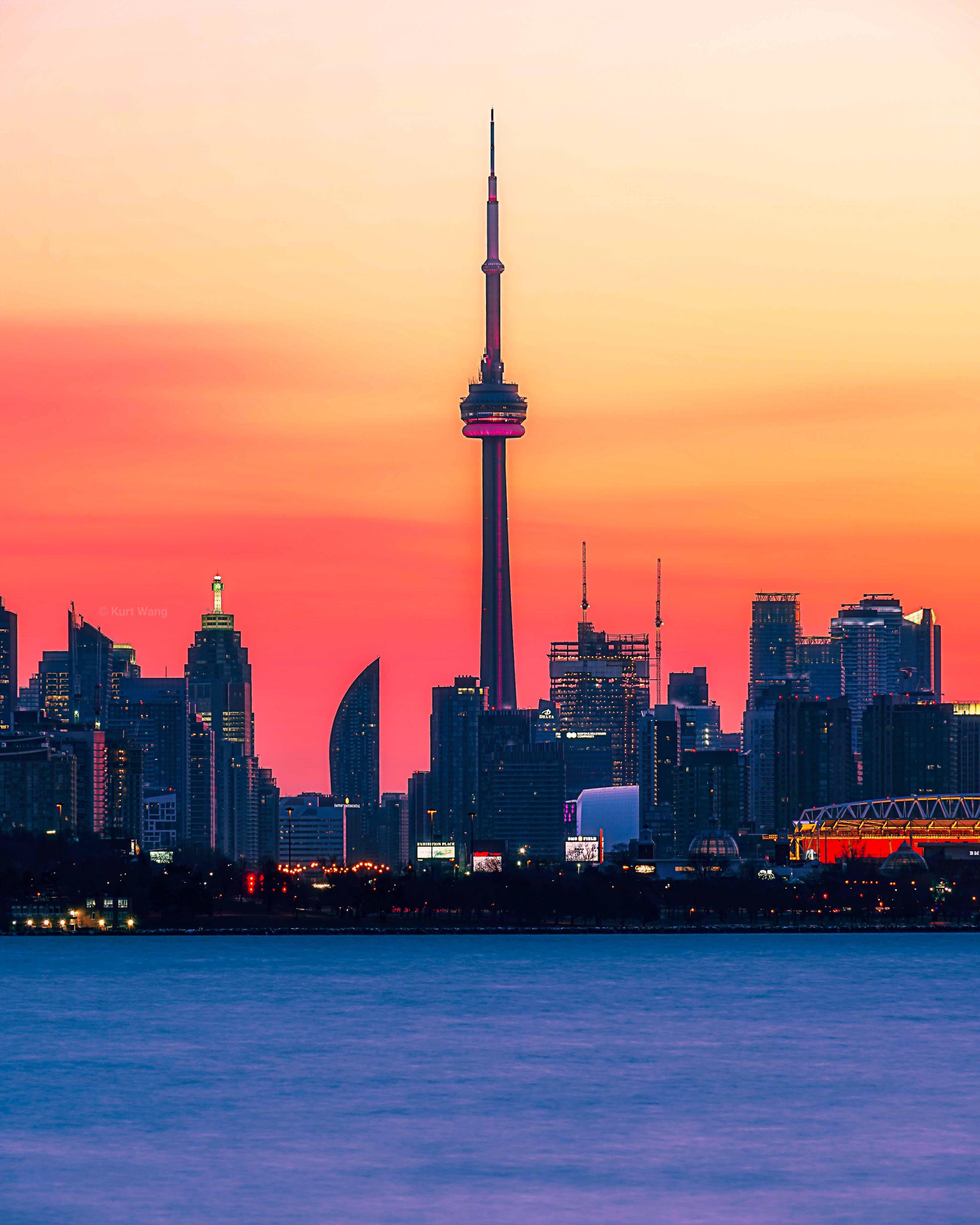 Toronto, Ontario skyline at sunset featuring the CN Tower and waterfront along Lake Ontario.