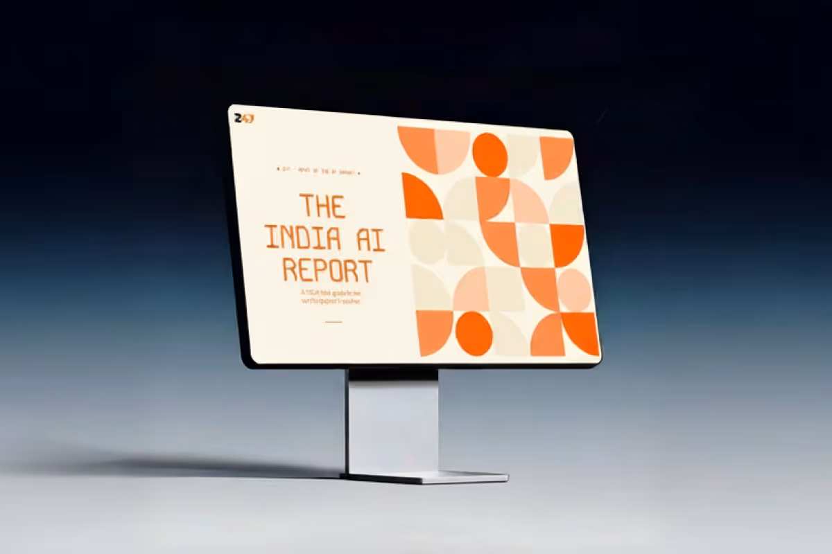 Computer monitor displaying a report titled 'The India AI Report' with abstract orange and cream geometric shapes.