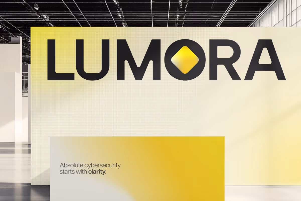 Large black and yellow Lumora logo on a light yellow wall above a yellow gradient sign reading 'Absolute cybersecurity starts with clarity.'