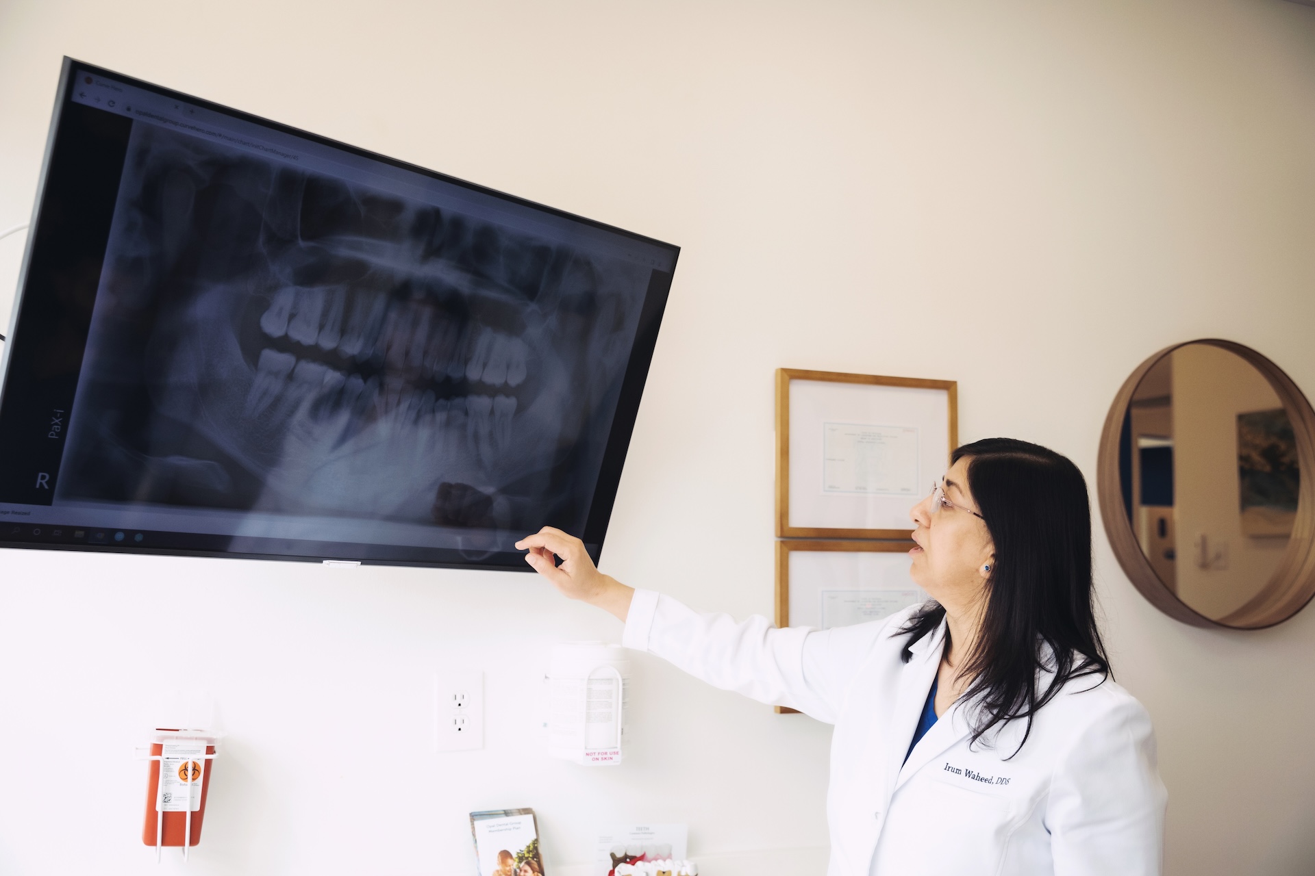 Dentist examines dental X-ray on screen at Opal Dental Group.