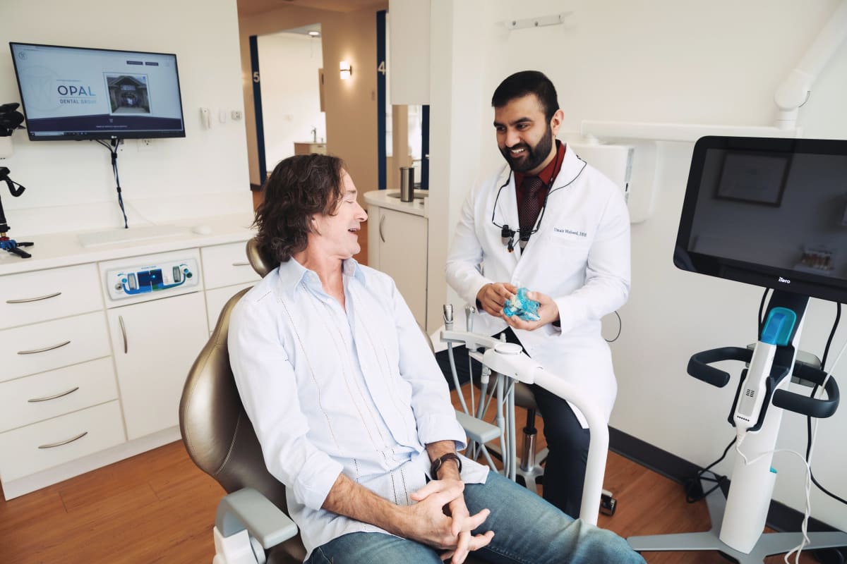 Dentist examining patient in clinical setting with dental equipment visible