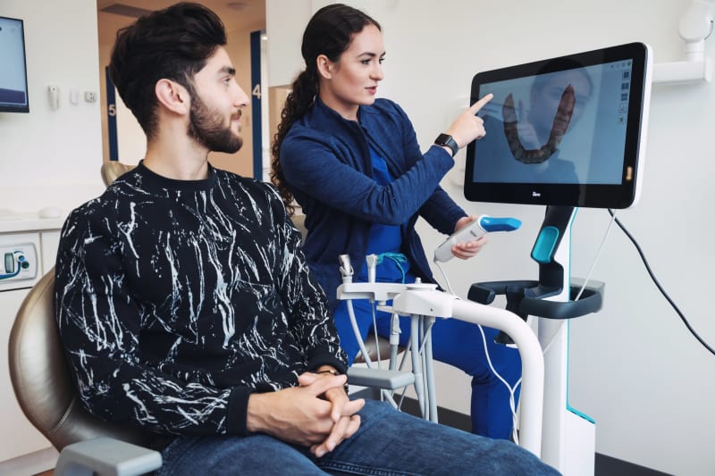 Dentist and patient reviewing digital scan results on computer monitor