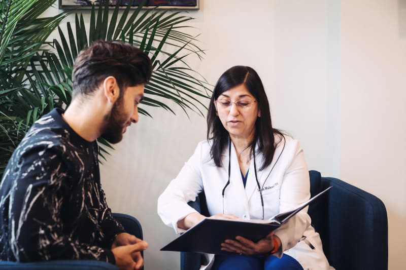 Female dentist in white coat having one-on-one discussion with male patient