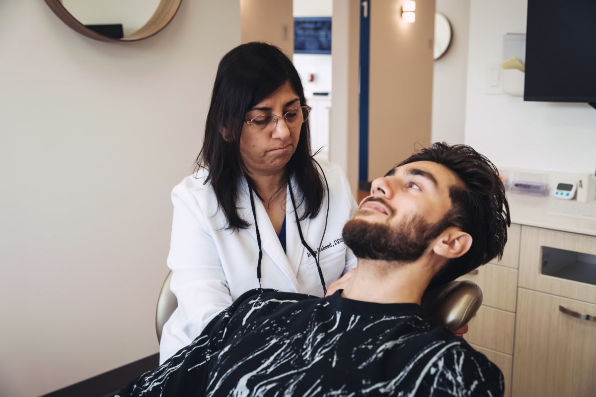 Dentist examining patient's mouth during clinical procedure in treatment chair