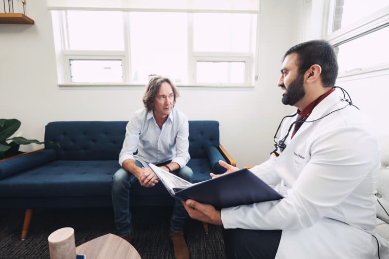 Female dentist in white coat consulting with male patient in clinical office setting
