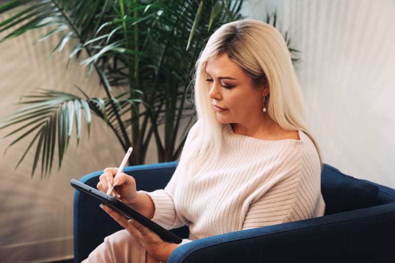Woman reading dental treatment information in waiting room with plant backdrop