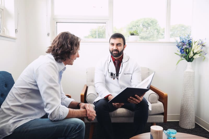 Male dentist consulting with patient on treatment plan in consultation room