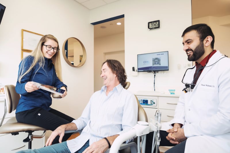 Two dentists and female patient in dental operatory during treatment consultation