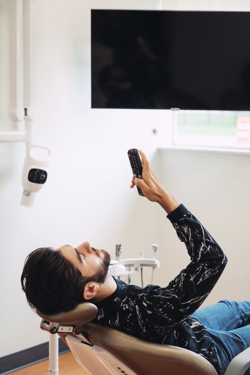 Patient viewing treatment results on overhead monitor in dental exam room