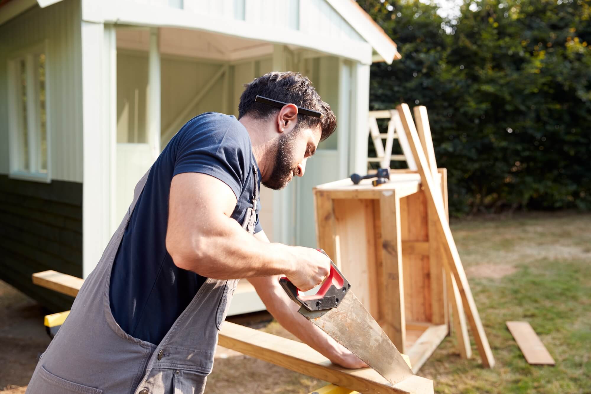 man awing wood building a chicken coop
