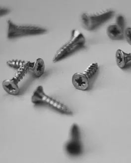 Close-up of several metallic screws scattered on a white surface.
