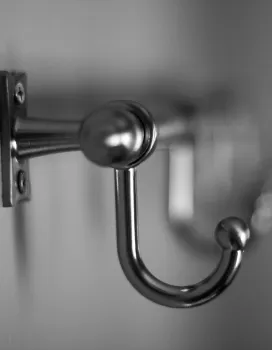 Close-up of a metallic coat hook mounted on a wall with several hooks fading into the background.
