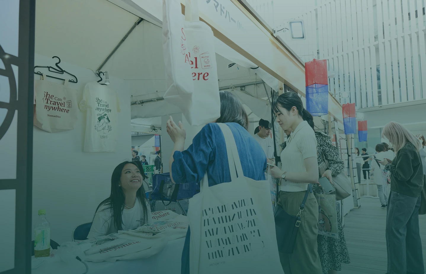 NomadHer team welcoming travelers at a She Can Travel Anywhere pop-up booth in Seoul