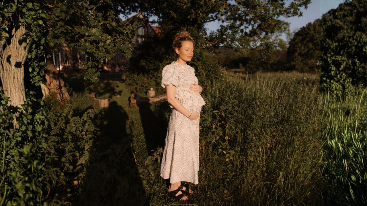 Pregnant woman walking through the garden at a mom'z retreat in the evening light