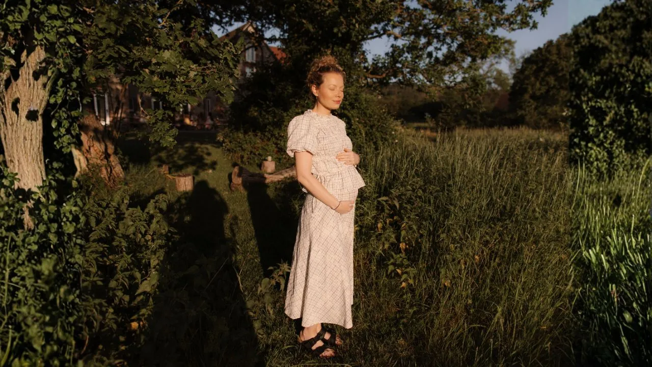 Pregnant woman standing in the garden in evening light at a mom'z retreat