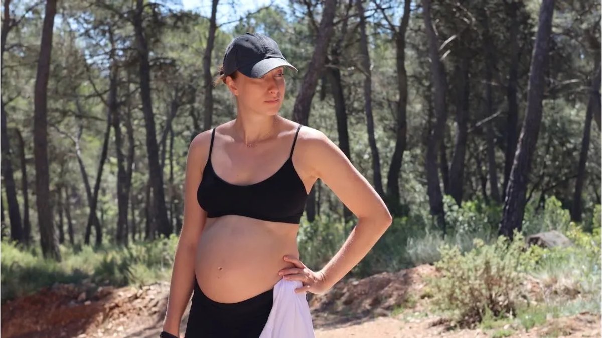 Pregnant woman pausing on a walk through pine woods at a mom'z retreat