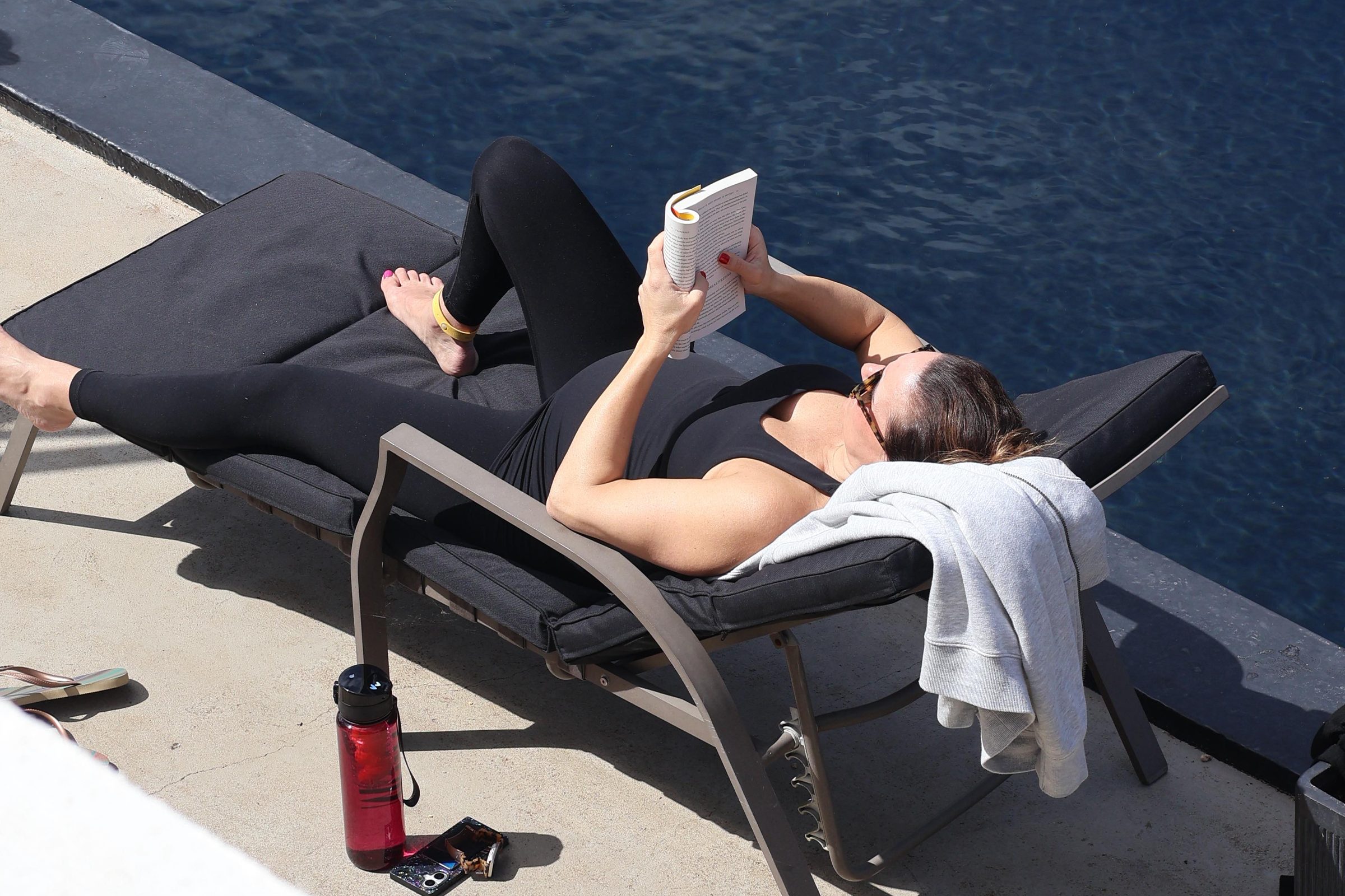 Pregnant woman reading on a lounger by the pool at a mom'z retreat