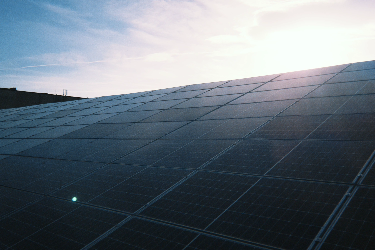 Solarmodule auf einem Gewerbedach im Gegenlicht.