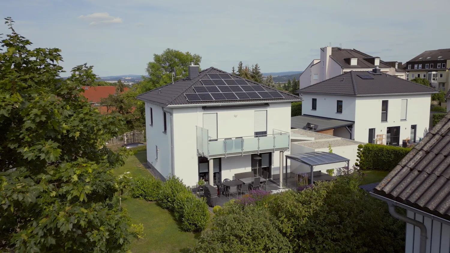 Einfamilienhaus mit Solaranlage auf dem Dach und überdachter Terrasse.