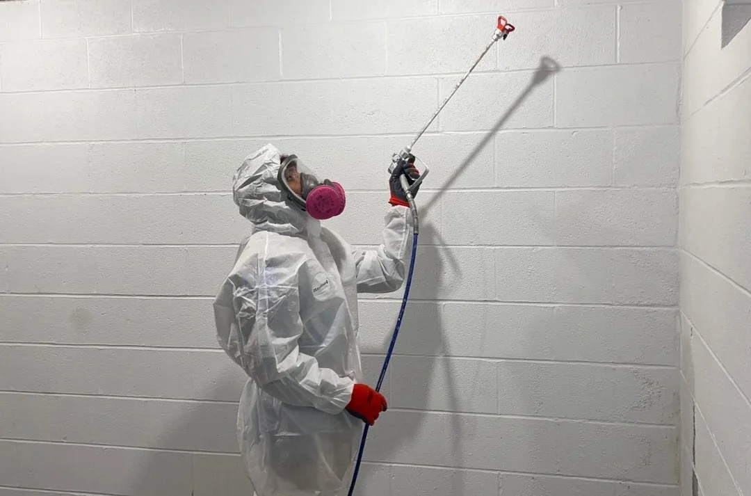worker using hose tool in cement block basement